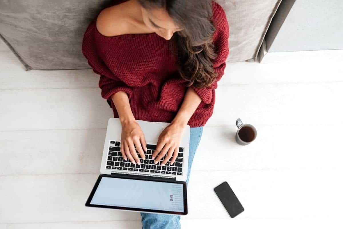 Woman with anxiety sitting on the floor and working from home on a laptop, for blog post low-stress jobs